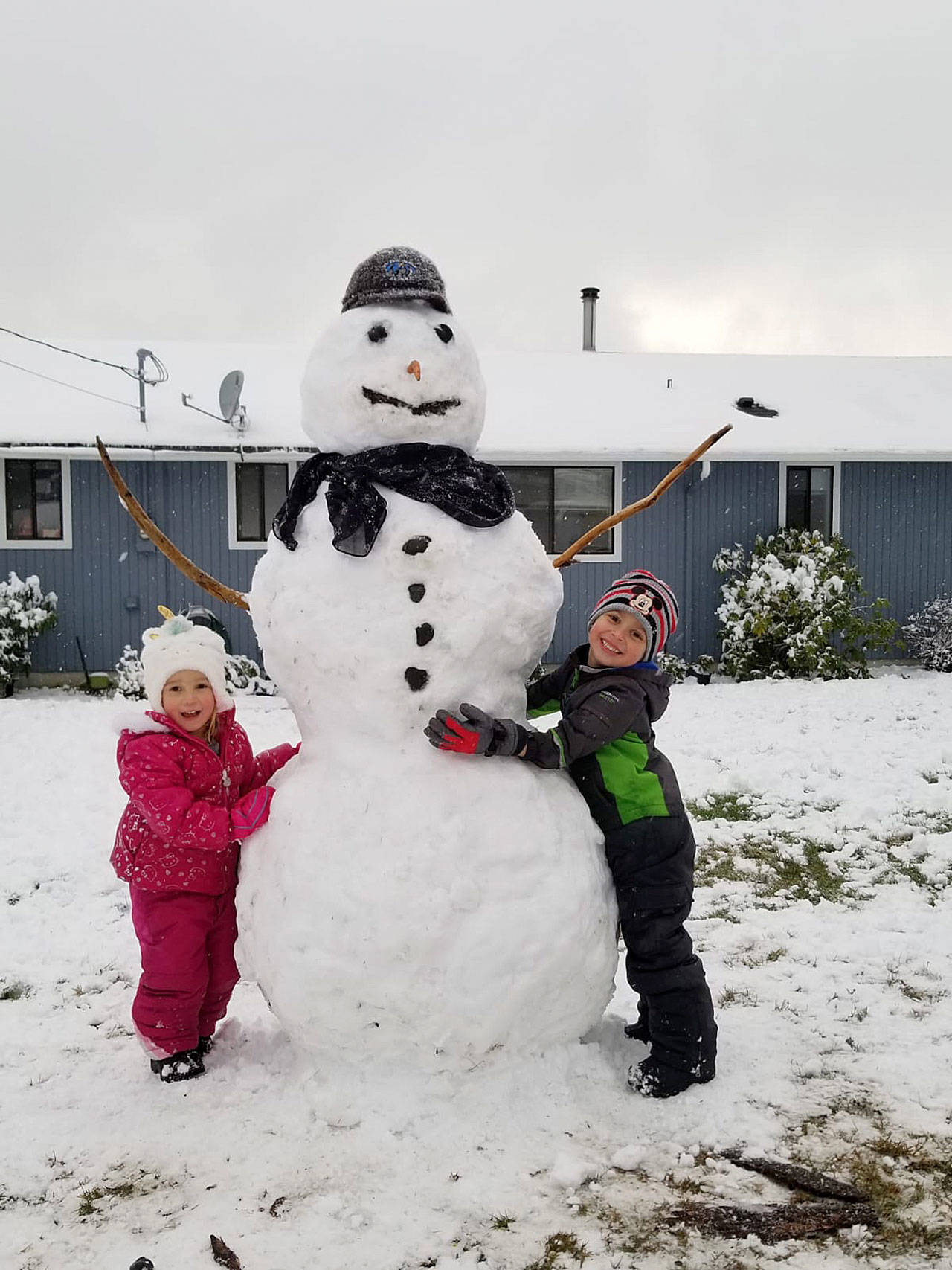 Luna and Nico Strong stand alongside their 6-foot snowman. During the many recent days of school closures, the Coupeville kids learned about the wonders of packing snow, something they’ve never done growing up in Colombia, South America. (Photo provided.)