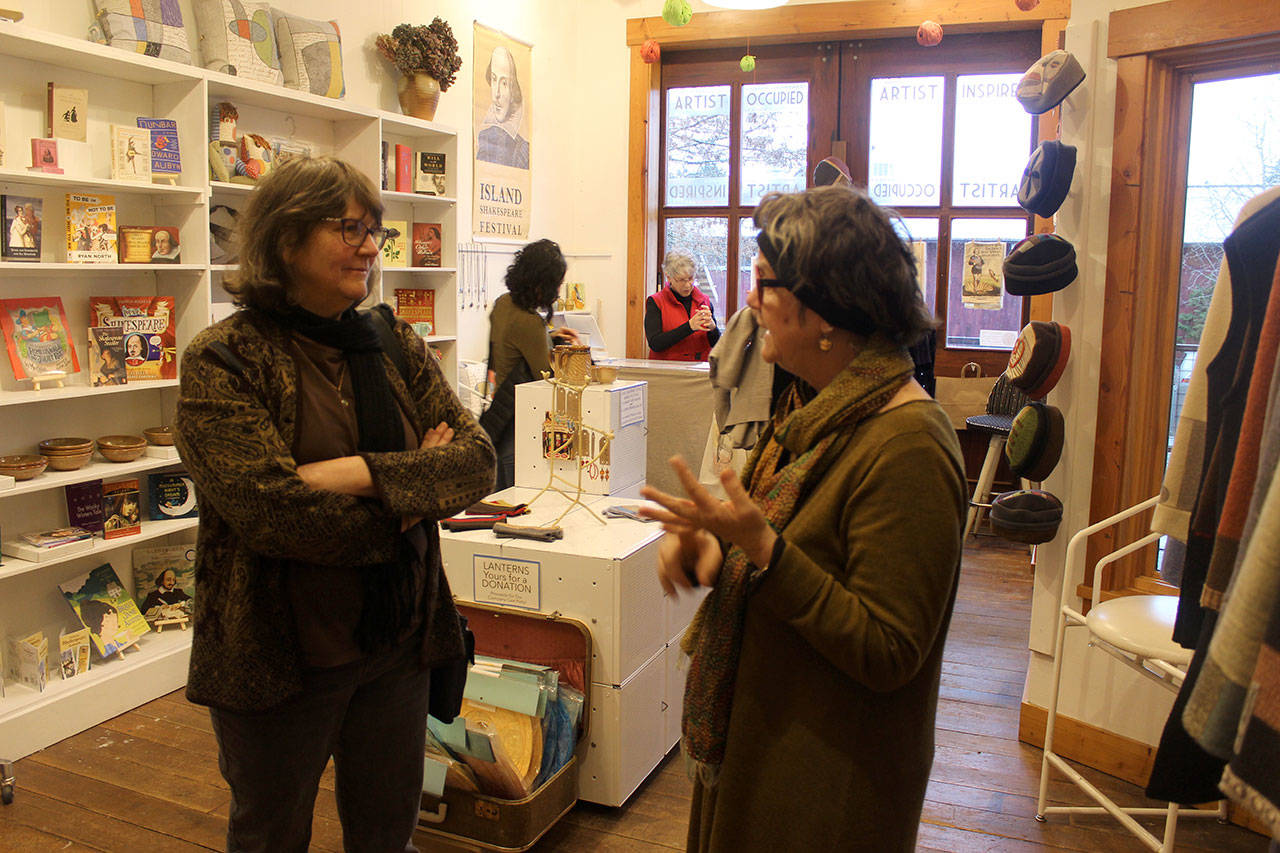 Peggy Juve, right, co-founder and board member of the Island Shakespeare Festival, speaks to a customer attending the grand opening of The Bard’s Boutique, a gift store benefitting the nonprofit festival in its 10th year. (Photo by Patricia Guthrie /Whidbey News Group)