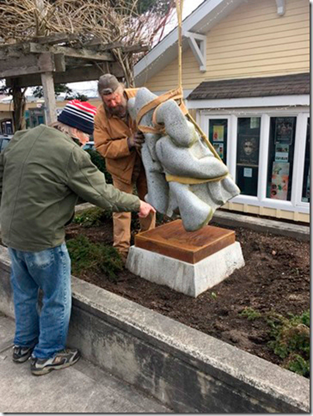 Artist Hank Nelson, left, and Stephen Formanek install Nelson’s sculpture “Wazmini III Courting His Bride” in front of the Langley Chamber of Commerce and Visitor Center. Nelson recalls starting to work on the piece, made of Cascade Granite, in the late 1990s. (Photo provided)