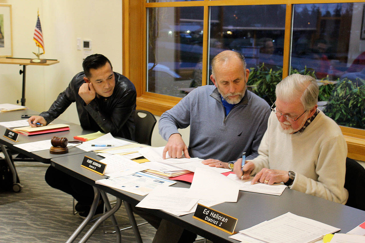 Port of South Whidbey commissioners Jack Ng, left, Curt Gordon and Ed Halloran review a list of grant application requests before announcing their decision at a meeting. (Photo by Patricia Guthrie/Whidbey News Group)