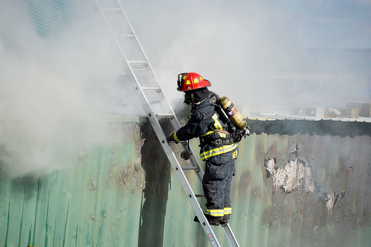 Lt. James Meek, Central Whidbey Island Fire and Rescue, inspects a storage container full of hay that caught fire Tuesday outside of Coupeville. Photo by Laura Guido/Whidbey News-Times