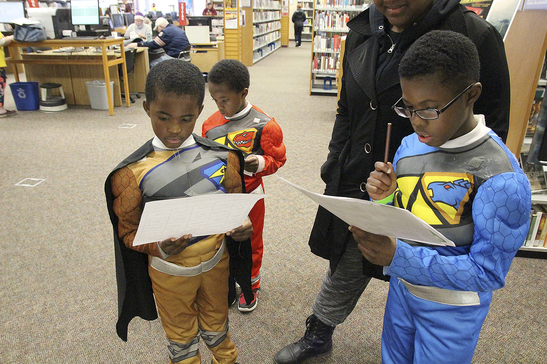 Photo by Laura Guido/Whidbey News-Times.                                Power Rangers Zjahnari Herrera, right, Azjahni Herrera, left, and Zjeziah Herrera, back, work on a scavenger hunt held throughout the Oak Harbor Library Saturday at WhidbeyCon. The free event is in its third year as a family-friendly way for locals to enjoy a comic convention.