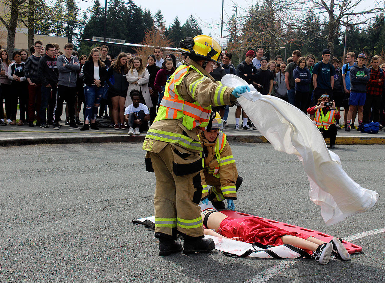 South Whidbey Fire/EMS responders place a white sheet over “victim” Emma Gilbert who “died” from head injuries after being thrown through the windshield of a car driven by her pretend— and real — boyfriend, Aryeh Rohde. Leadership students organized the demonstration that also involved an assembly. (Photo by Patricia Guthrie/Whidbey News Group)