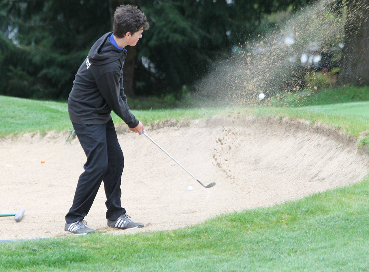 Sand flies as Gabe Jacobson-Ross fires out of a trap in Tuesday’s match with King’s.(Photo by Jim Waller/South Whidbey Record)