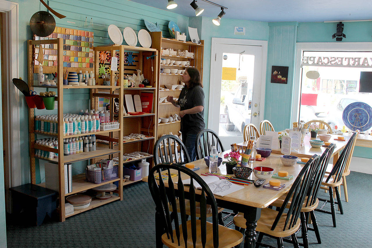 Owner Carol Evans arranges shelves at the new Langley location of Whidbey Art Escape, a paint-your-own ceramics outlet that had been in Freeland for more than a decade. (Photo by Patricia Guthrie/Whidbey News Group)