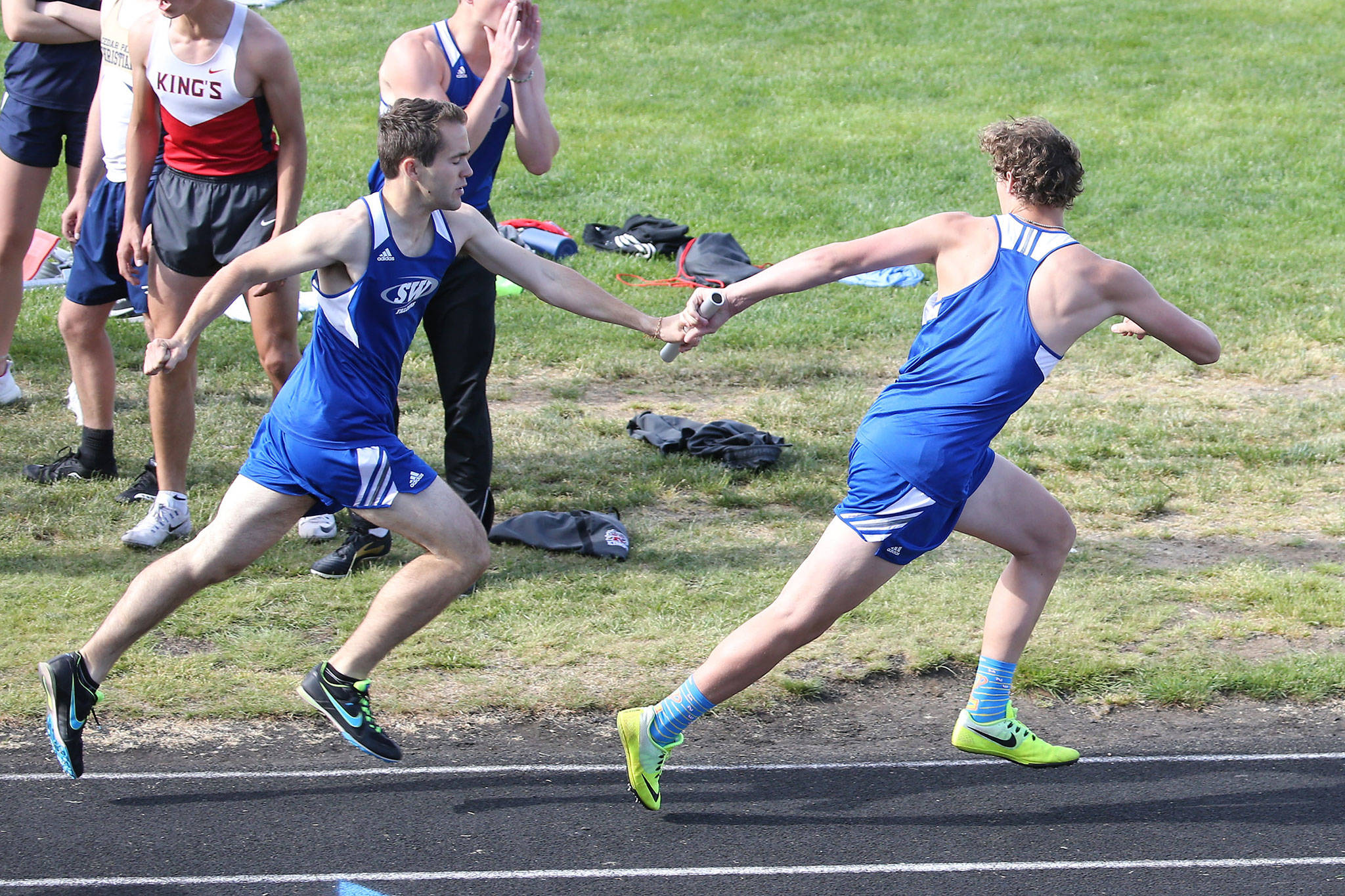 Max Dodd hands off to Cody Eager in the 4x400 relay.(Photo by John Fisken)