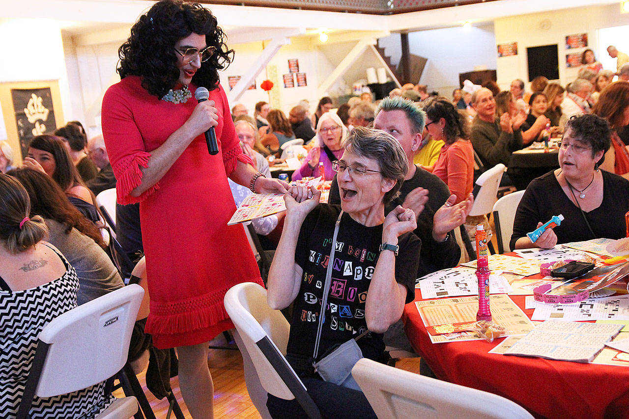 (Photo by Laura Guido/Whidbey News Group)                                Shannon O’Phelan celebrates after winning a round at Not Your Grandma’s Bingo Saturday night at Bayview Hall. One of the hosts, Bobbi Jo Blessings, who also goes by Kerry Nielsen, verifies her card.