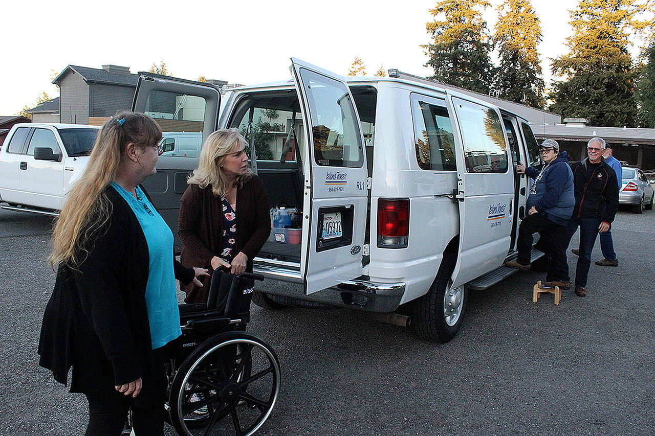 Volunteer Kat Ersch, far left, helps Dana Sawyers, coordinator of the Whidbey Veterans Resource Center, place a wheelchair into the van that makes weekly trips to Seattle to take veterans to medical appointments. (Photo by Patricia Guthrie/Whidbey News Group)