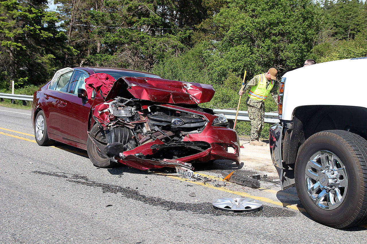 Photo by Laura Guido/Whidbey News-Times                                North Whidbey Fire/EMS Firefighter Ian Eby cleans up the scene of a head-on traffic accident Wednesday afternoon. Three people were sent to the hospital with non-life-threatening injuries. Highway 20 just south of Oak Harbor was closed for about an hour.
