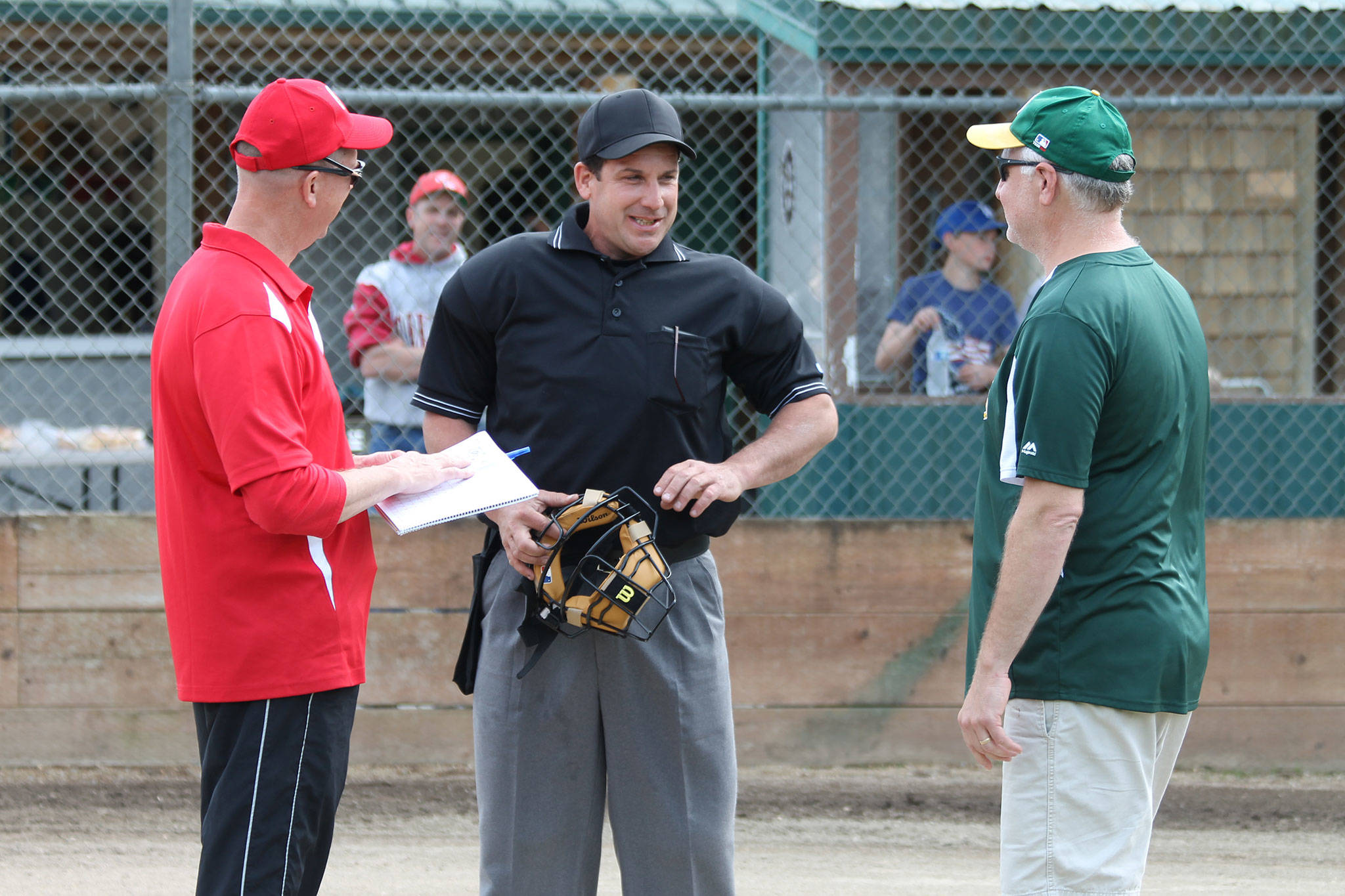 Umpire Jim Honold, center, goes over the ground rules with Central Whidbey coach Jon Roberts, left, and South Whidbey Athletics’ coach Steve Zarifis. (Photo by Jim Waller/South Whidbey Record)