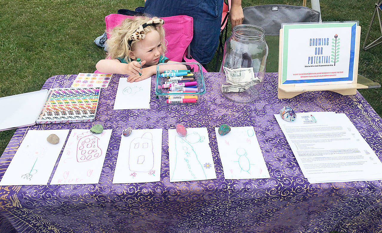 River Stewart, 4, works on art at the Bayview Farmers market last week. She returns today and next Saturday to continue offering her art for donations to South Whidbey Elementary School programs. Photo provided
