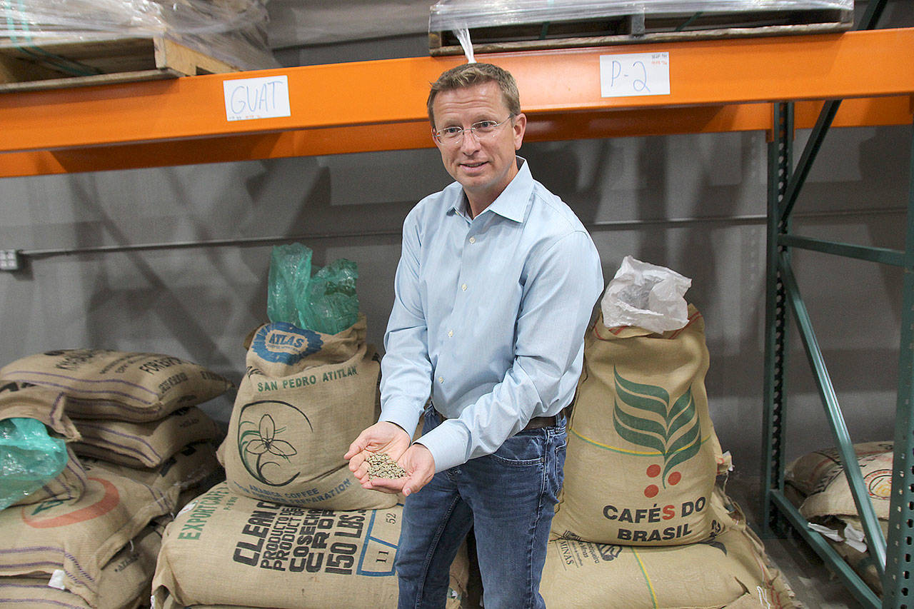 <em>Whidbey Coffee owner Dan Ollis holds a handful of green coffee beans that will be roasted at the company’s facility in Mukilteo.</em> (Photo by Jessie Stensland / Whidbey News Group)