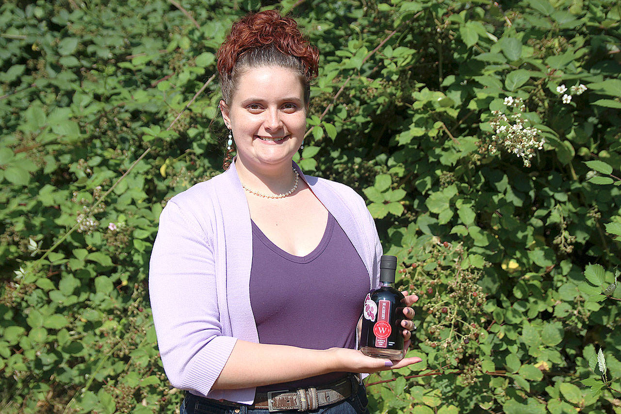 Mercedes Monarch, production associate at Whidbey Island Distillery, holds a bottle of the company’s Community Batch of blackberry liqueur. It’s made using donated berries and $2 from every bottle sold go toward local nonprofits. The distillery is currently accepting blackberries for next year’s batch and will donate money for every pound collected. Photos by Laura Guido/Whidbey News Group