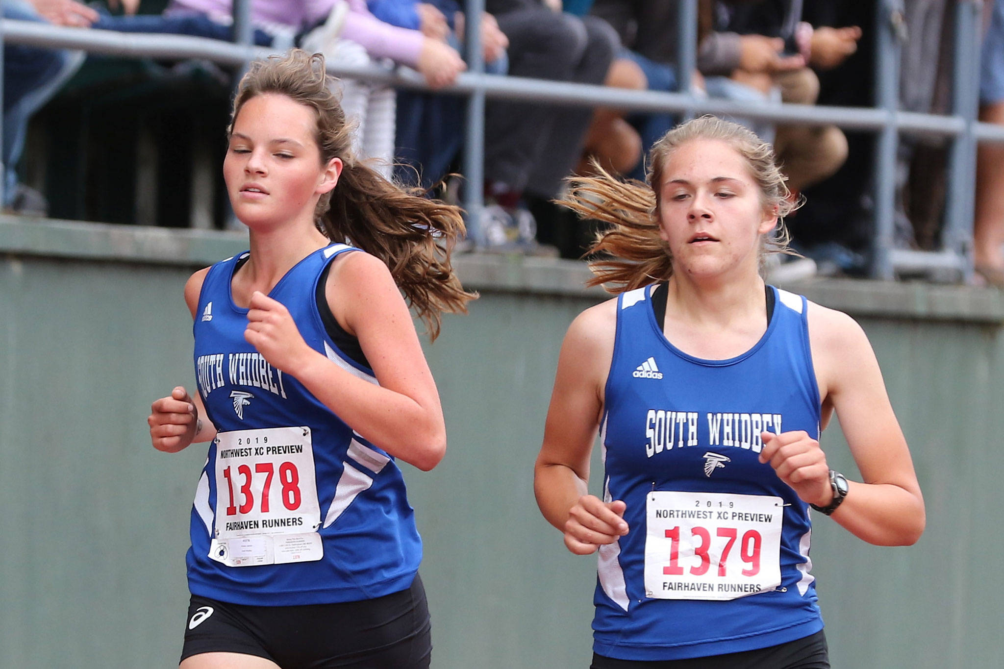 South Whidbey’s Jasmin Graner, left, and Grace Huffman run together toward the finish line at the Sehome Invitational. (Photo by John Fisken)