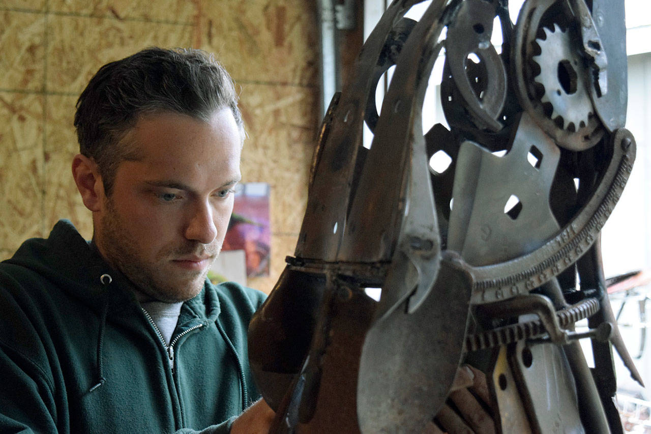 In his Clinton garage studio, Aidan Rayner works on his howling wolf sculpture that is comprised of discarded machine parts, tools and other metal found at Island Recycling. The artwork is slated to be a memorial for his twin brother, Dylan Rayner, who died in 2016. (Photo by Patricia Guthrie)