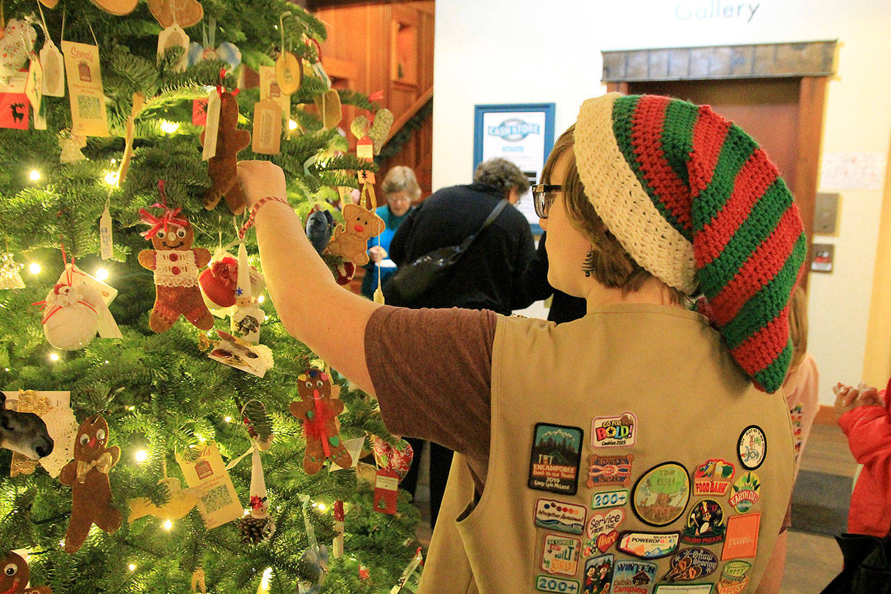 Photo by Kira Erickson/Whidbey News Group                                Girl Scout Kalea Staats places an ornament on the Giving Tree in the Bayview Cash Store on Dec. 5.