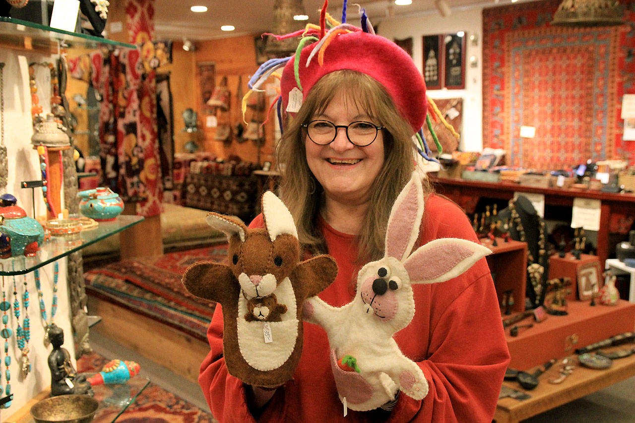 Photos by Kira Erickson / Whidbey News Group                                Employee Deborah Eimers models a felt hat and two puppets from Music For the Eyes, a Langley store offering cultural pieces from around the world.
