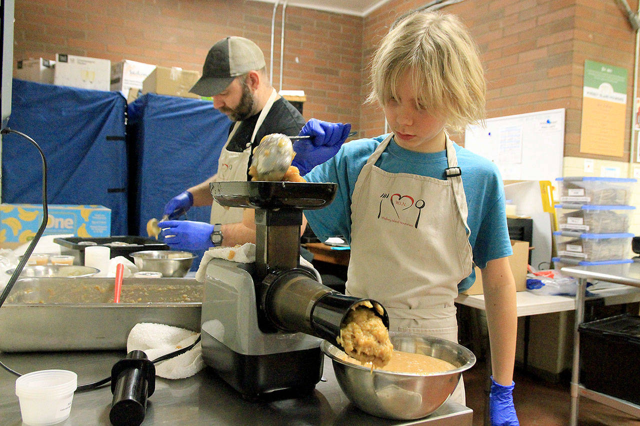 Photo by Kira Erickson/Whidbey News Group                                Caeleb Wiph, one of WIN’s youngest volunteers, helps make applesauce on Jan. 29.