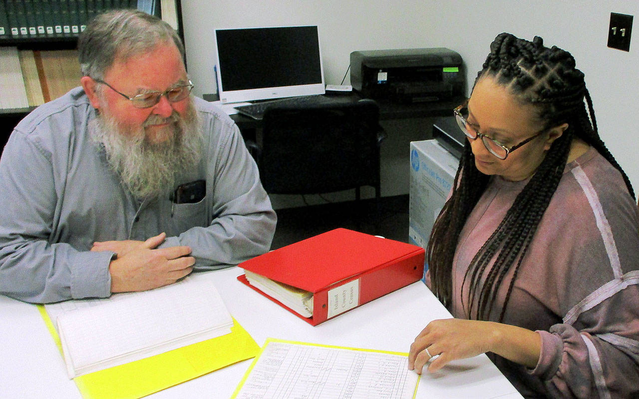 Photo by Dave Felice                                At the Island County Historical Museums Langley Archive Research Center, genealogy researcher Guy Calkins of Freeland and Museum Archivist Cassie Rittierodt discuss Whidbey Island census records. The museum keeps a notebook containing transcribed entries of all island census records from 1850 to the present day.