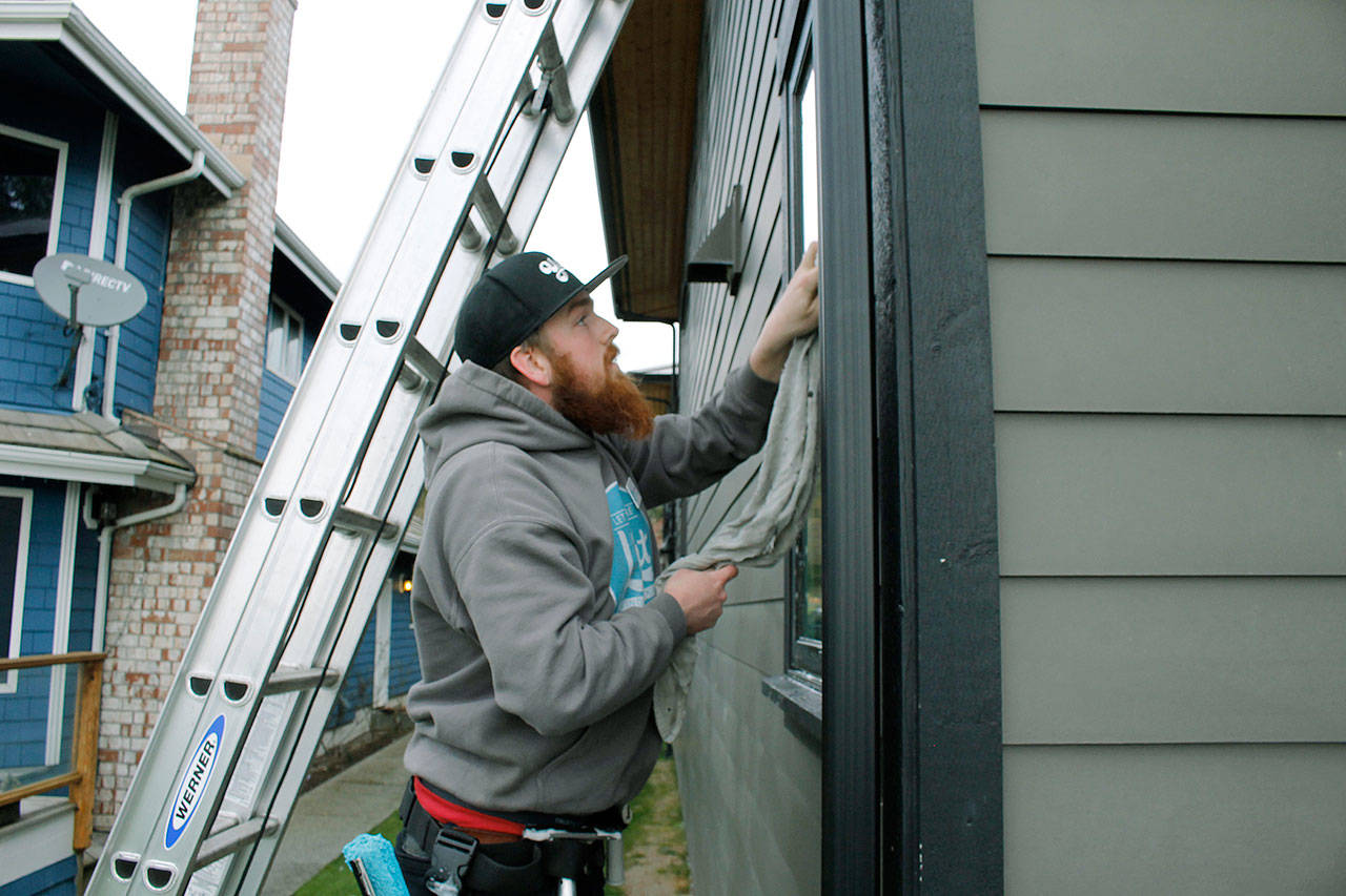 Photo by Kira Erickson/Whidbey News Group                                Worker Joe Williams reaches a high window with a ladder. Many windows the business cleans are hard to access and require the help of ladders.