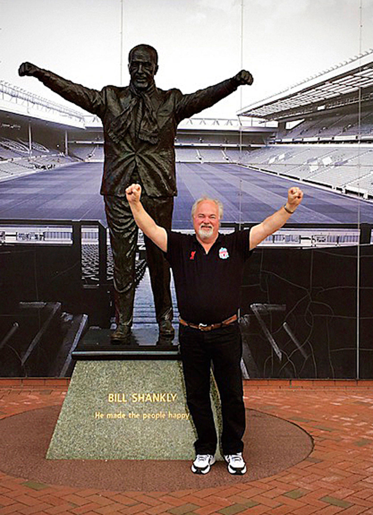 Crispin Roberts stands next to the statue of Bill Shankly outside Liverpools soccer stadium. (Provided photo)