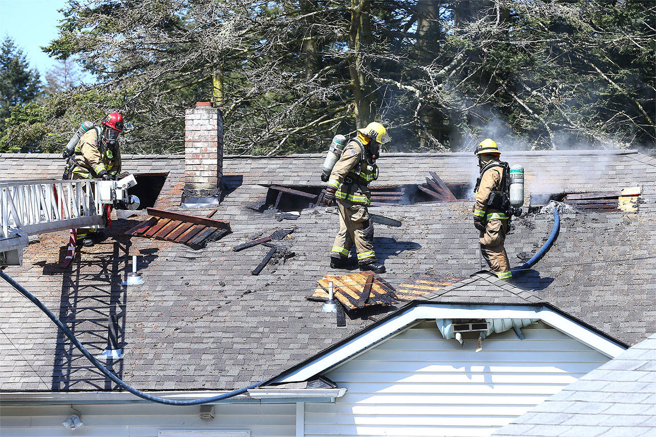 Photo by John Fisken                                Firefighters cut open the roof of a North Whidbey home to extinguish a fire in a concealed space.