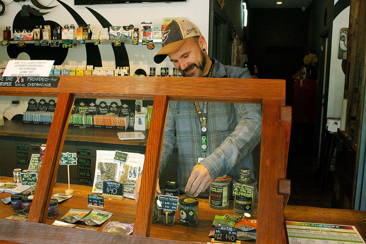 Photo by Kira Erickson/Whidbey News-Times                                Budtender Tyler Small arranges a display behind a window in Island Herb. The Freeland cannabis store experienced record-breaking sales in March.