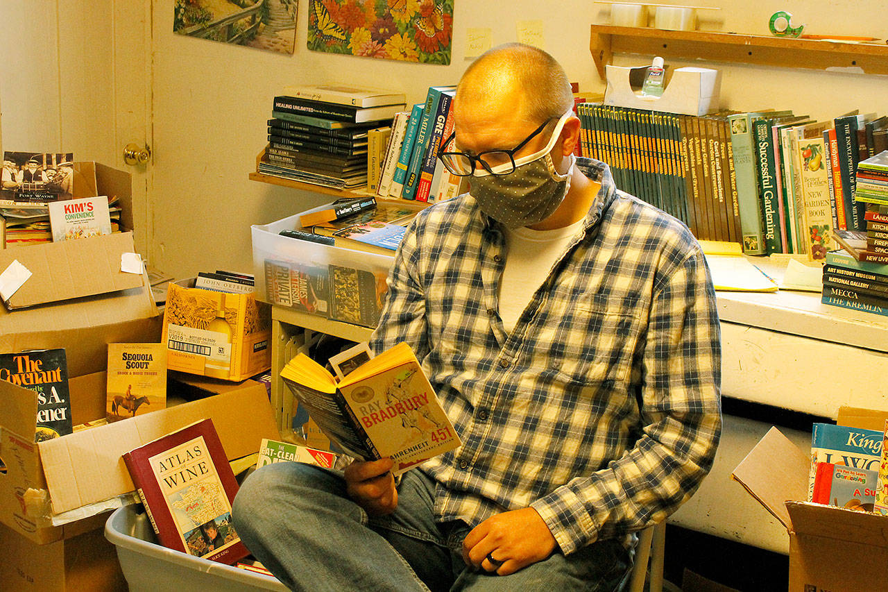 Photo by Kira Erickson/Whidbey News-Times                                Surrounded by the 500 books he has collected during the last two weeks, Kevin Tyler Lucas reads one of his favorite novels, Fahrenheit 451.