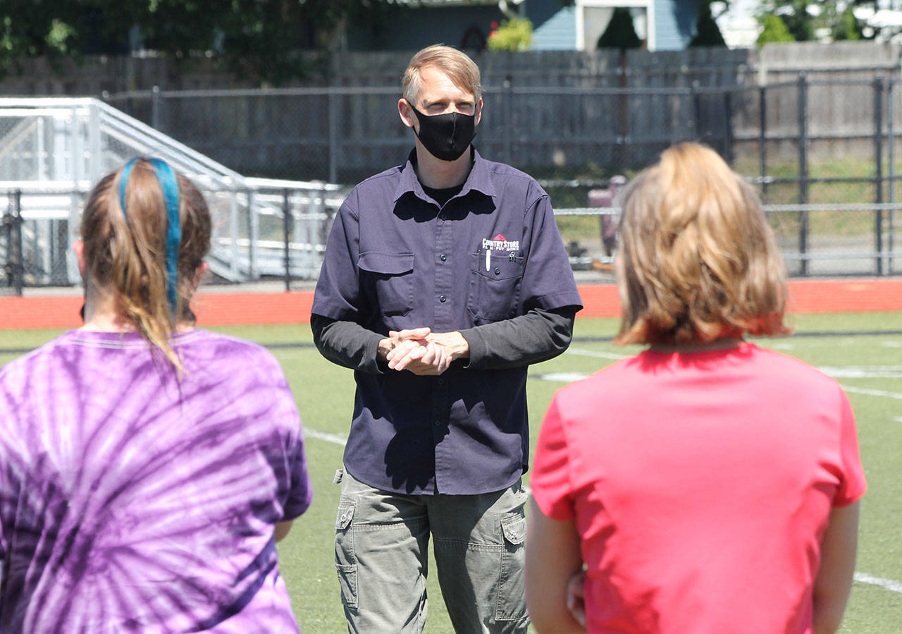Oak Harbor High School junior varsity coach James Croft, wearing a mask, addresses the team before a drill Monday. (Photo by Jim Waller/Whidbey News-Times)
