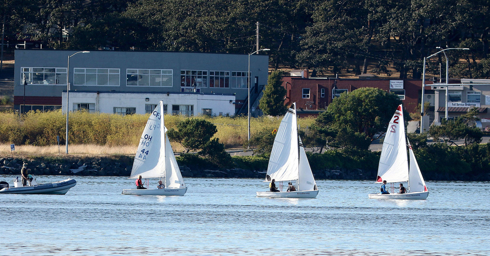 Photo by John Fisken                                New Wildcat Sailing coach Shawn O’Connor, left, instructs his team during a recent practice.