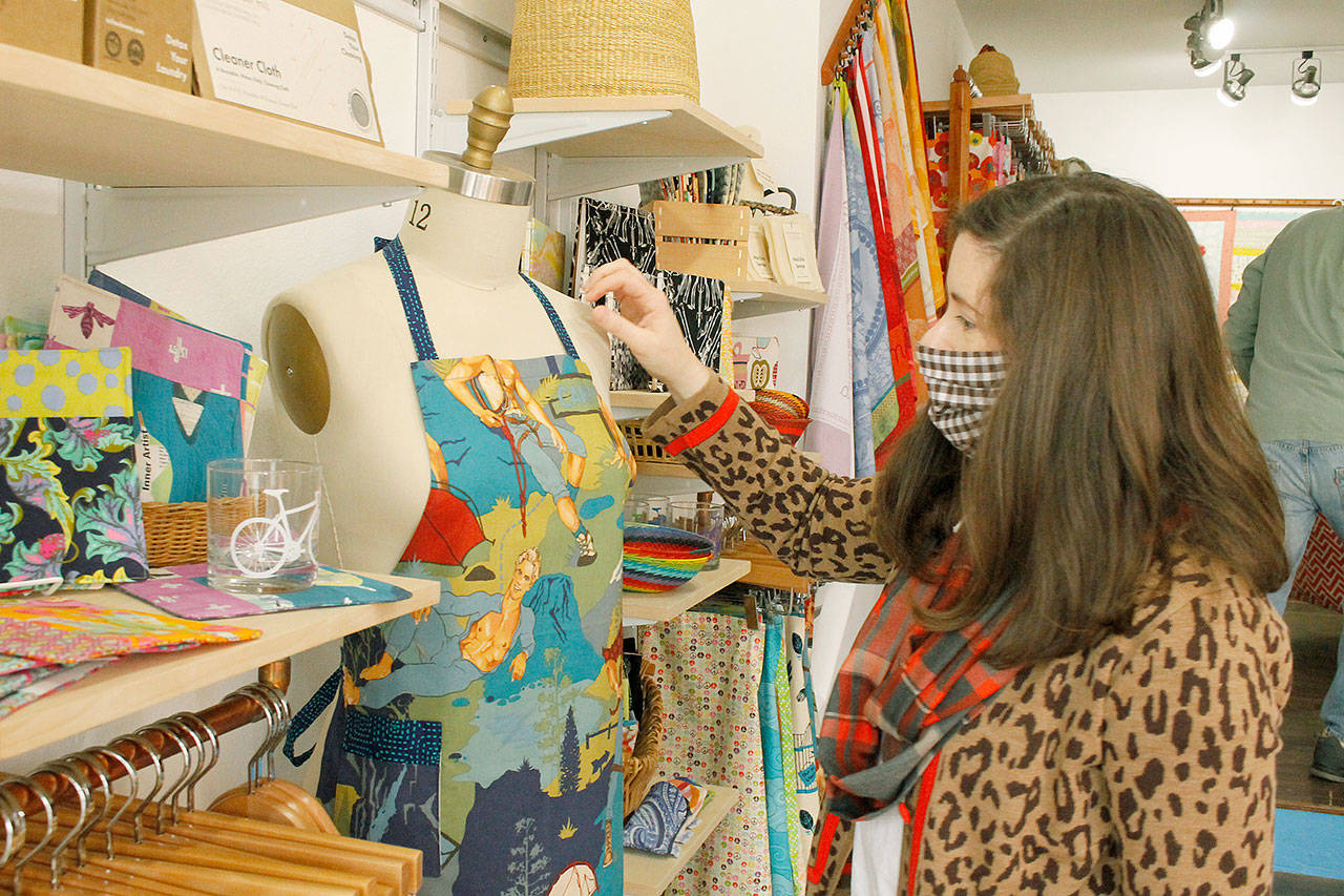 Owner Jennifer Robinson of the Blue Peony opened up her first storefront of fabric products in Langley in July. One of her favorite aprons she made, hunks gardening, is displayed in the store. Photo by Kira Erickson/Whidbey News-Times