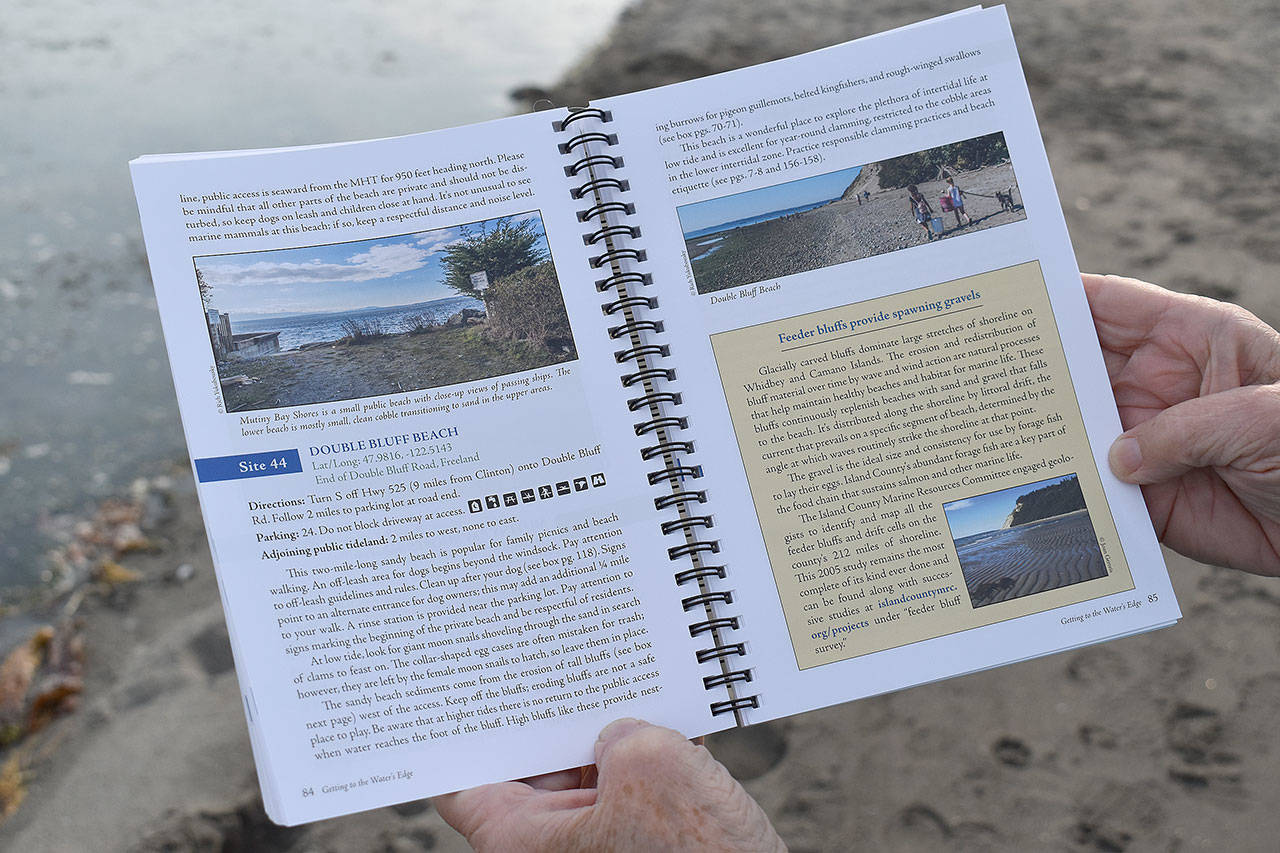 Jeanie McElwain opens the third edition of “Getting to the Water’s Edge” to popular South Whidbey beach Double Bluff. More than 50 volunteers made the current book possible. Photo by Emily Gilbert/Whidbey News-Times