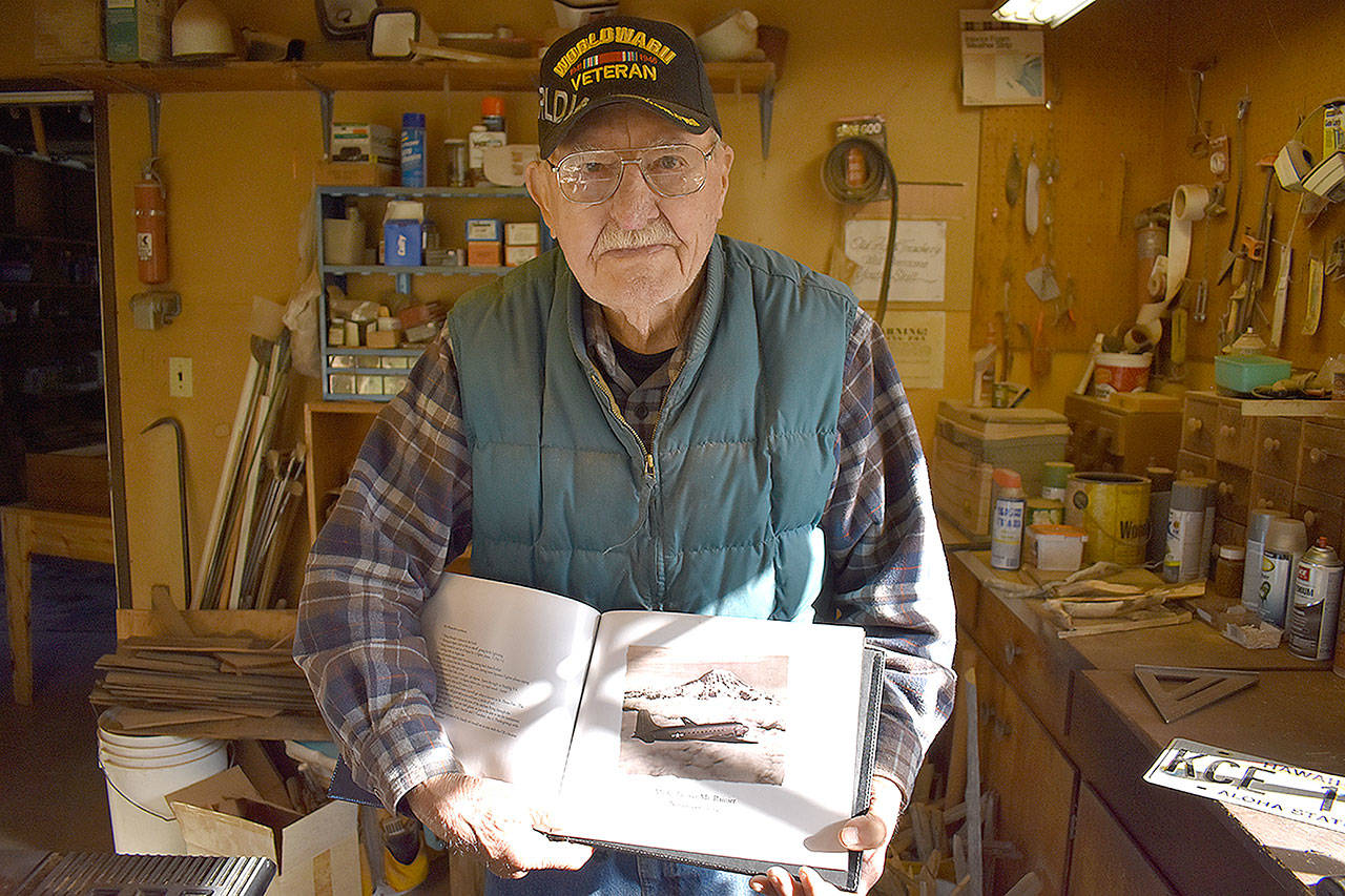Photo by Emily Gilbert/Whidbey News-Times
Commander Clayton Engebretsen flew critical supplies for the Navy during World War II in the Pacific Theater. His family compiled photos of his service, including this one of him flying a plane over Mount Rainier in 1965, taken by a fellow pilot.