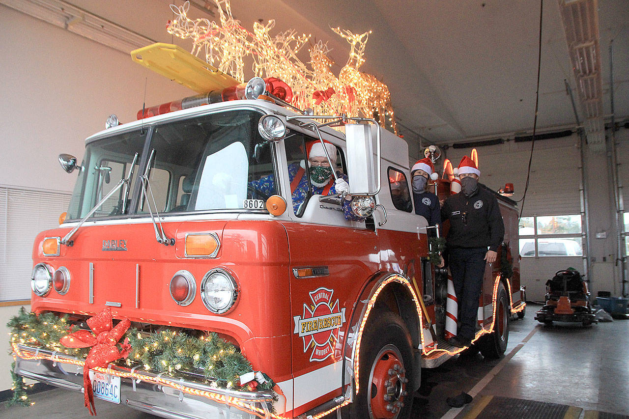 Santa and his elves, Jen Porter and Dalton Martin, have begun decorating Central Whidbey Fire and Rescue’s Santa Mobile, which begins making the rounds on Dec. 7. Photo by Emily Gilbert/Whidbey News-Times.