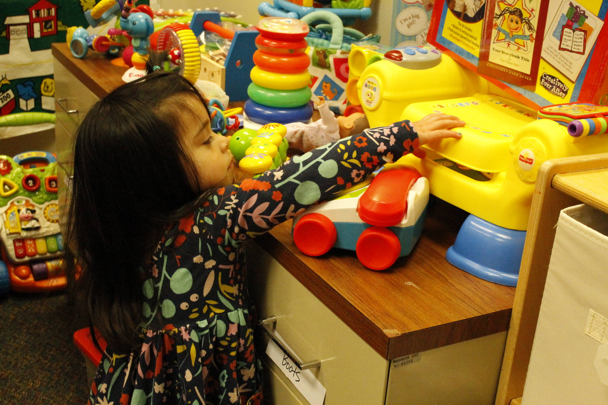 Santosa’s daughter Gwen, 2, tests out some of the toys in the new Mother Mentors “boutique.” Photo by Kira Erickson/South Whidbey Record