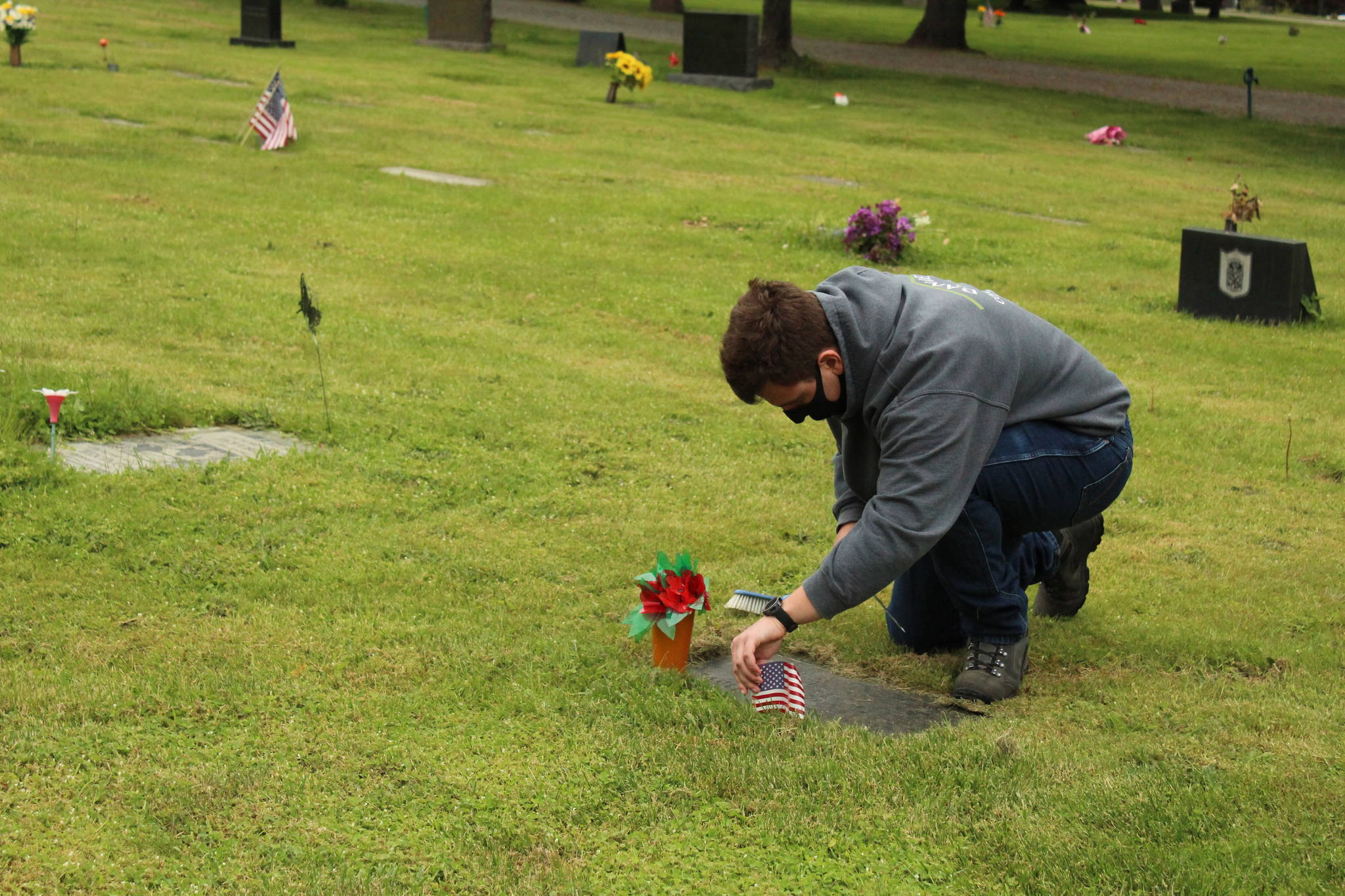 Pablo Closson decorates a veteran’s grave at Maple Leaf Cemetery.