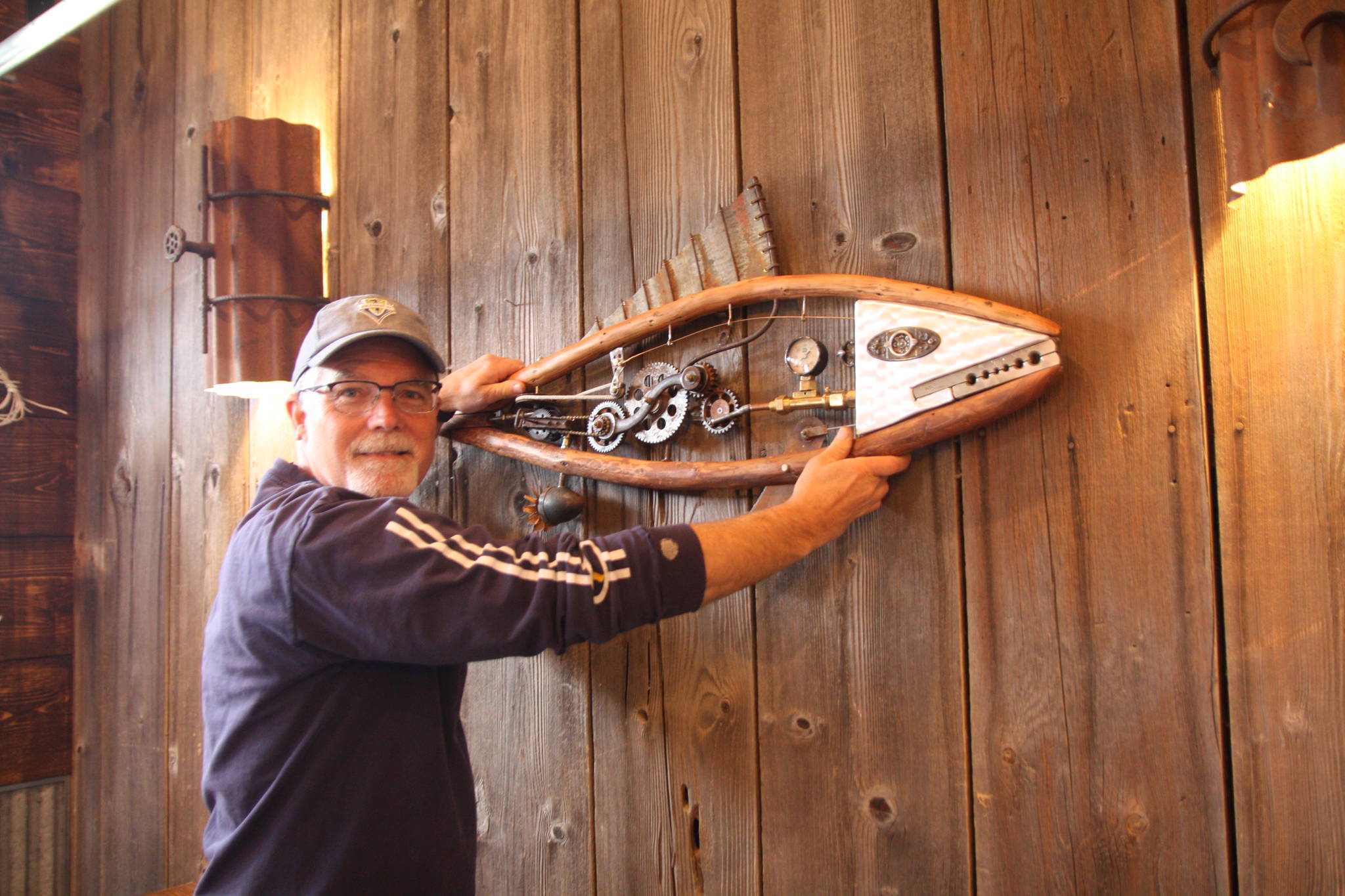 Artist Mark Wacker hangs a fish ornament he created for the taproom barn. (Photo by Jessie Stensland/South Whidbey Record)