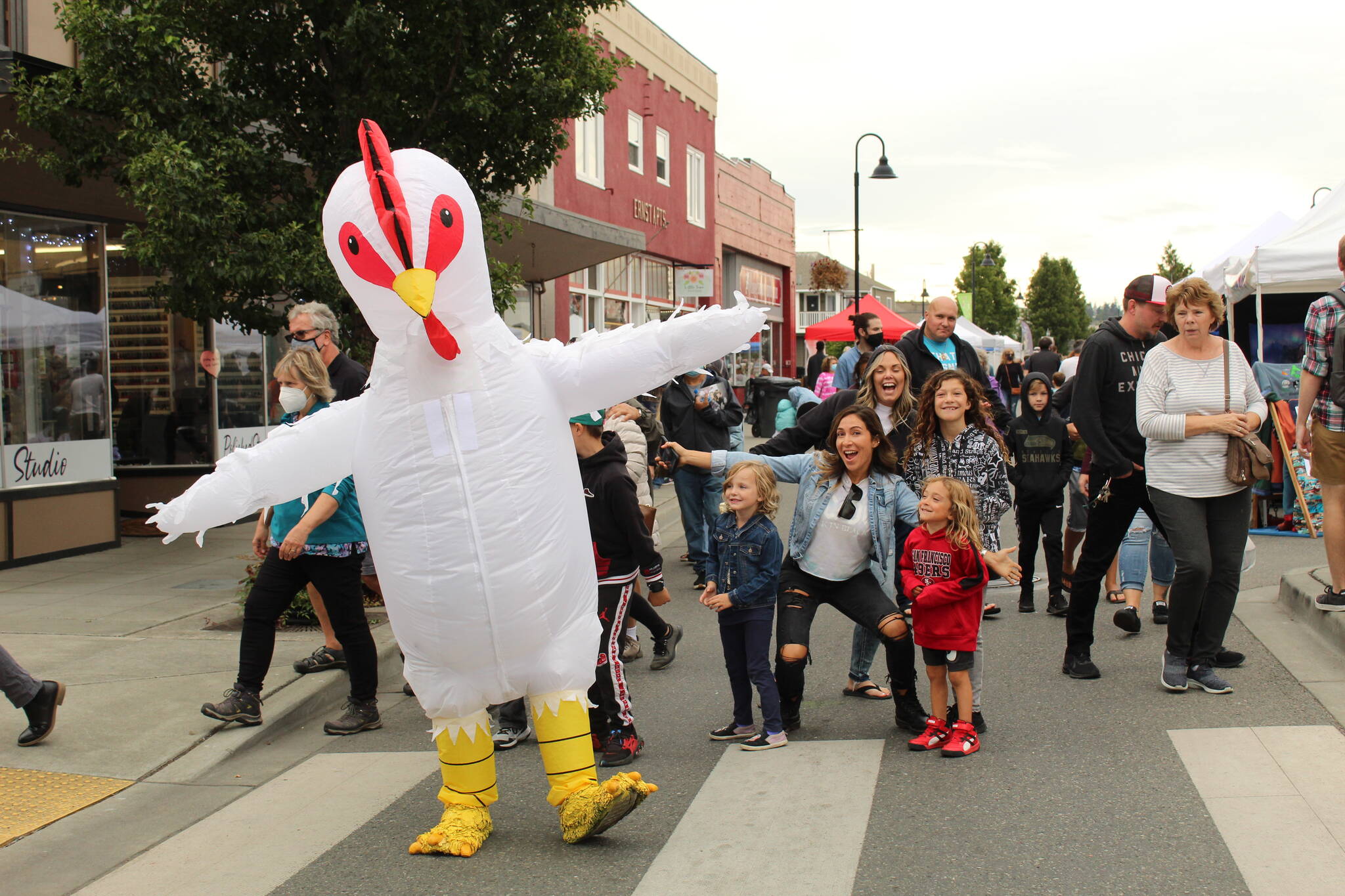 Harbor’s famous chicken dances with the crowds at the Oak Harbor Music Festival Saturday. Ever the trendsetter, it appears a flock of fans have copied his signature pose while he struts about the town during the multi-day music festival. (Photo by Karina Andrew/Whidbey News-Times)