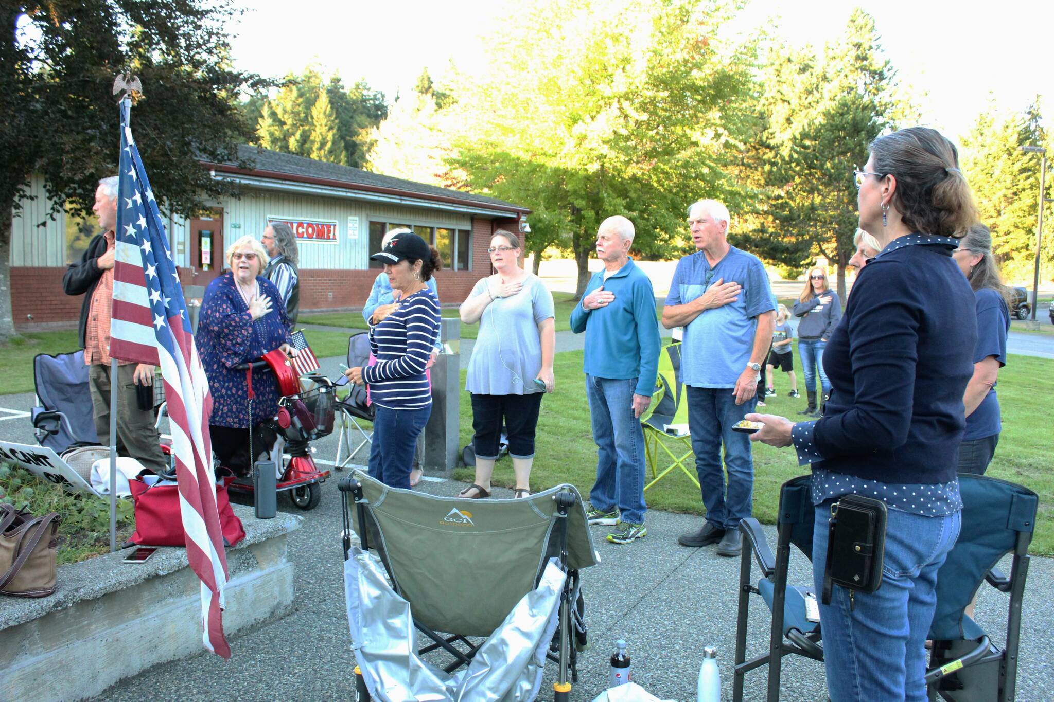 Community members stand and recite the Pledge of Allegiance while listening to a South Whidbey School District board meeting. (Photo by Karina Andrew/Whidbey News-Times)