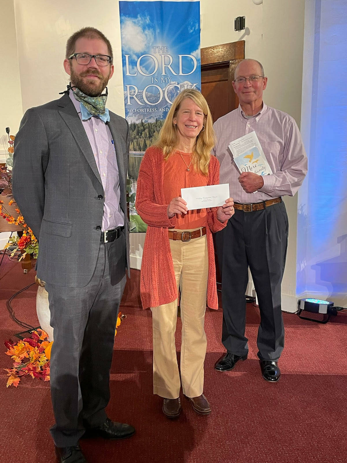 Pastor Greg Steible, left, and church stewardship chair Jim Rohrback present Mother Mentors Director Kate McVay with a check for $10,000 on Sept. 12. (Photo provided)