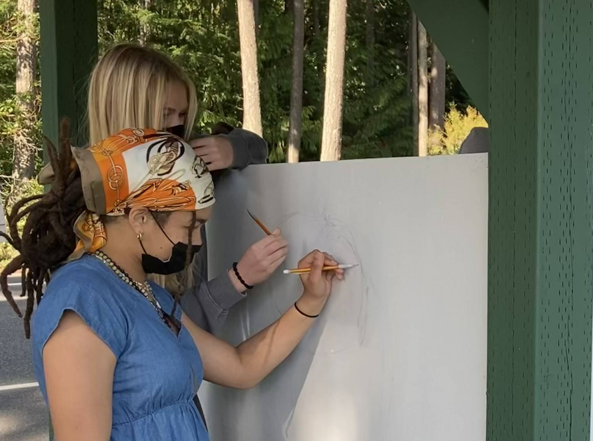Junior Simone White, front, and senior Mikenna Wicher sketch on the side of the new farmstand. (Photo provided)