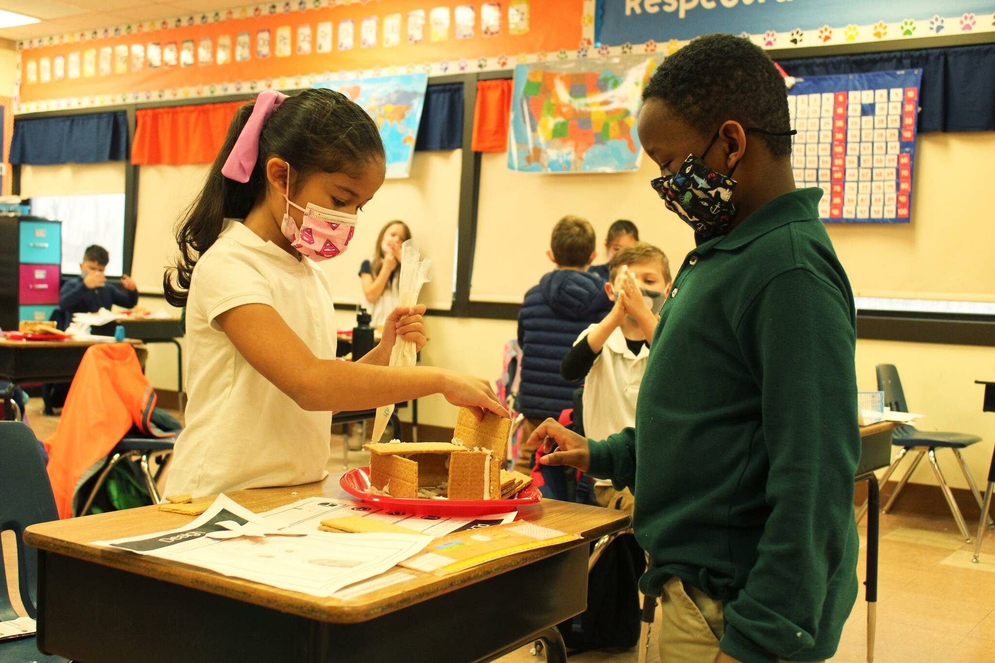 Photo by Karina Andrew/Whidbey News-Times
Second grade students Adaleigh Navarro and Demarius Robinson try to make the graham cracker walls stick to their frosting cement in class Dec. 16.
