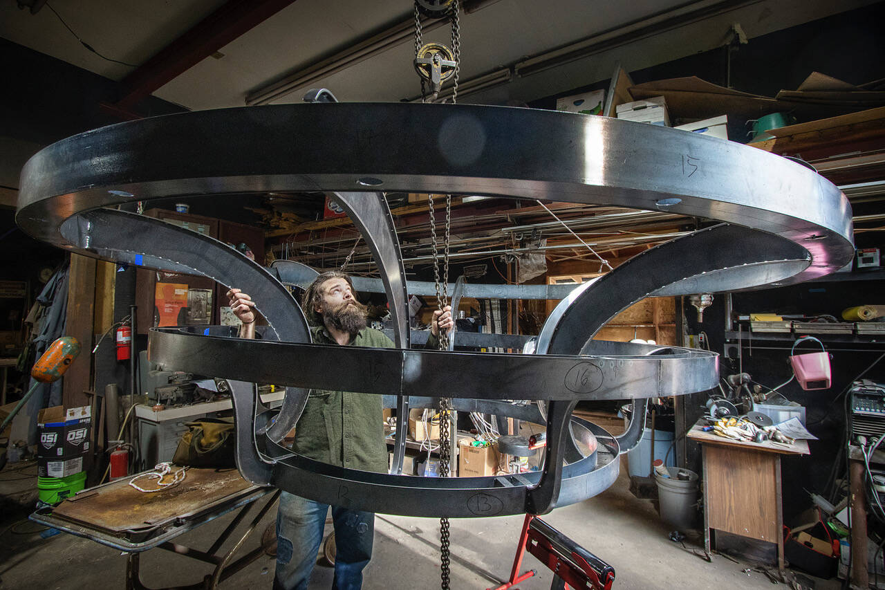 Photo by David Welton
Brendan McHugh uses a hoist to lower the 400-pound chandelier at the shop on Saratoga Road.