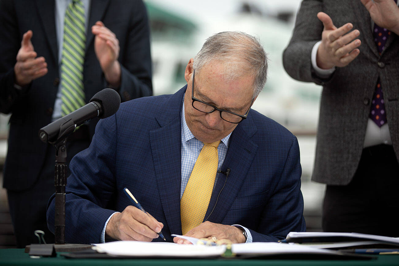Ryan Berry / The Herald
Gov. Jay Inslee signs SB 5974 into law during a bill signing March 25 outside the ferry terminal in Mukilteo.
