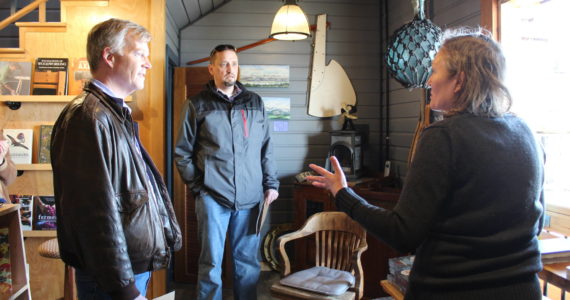 Photo by Karina Andrew/Whidbey News Group
<em>State Reps. Dave Paul, left, and Greg Gilday learn about the historic preservation work that took place in Kingfisher Bookstore from Meg Olsen, the store’s owner. The original harbor door on the building’s lower level was used when the building housed a confectionary.</em>