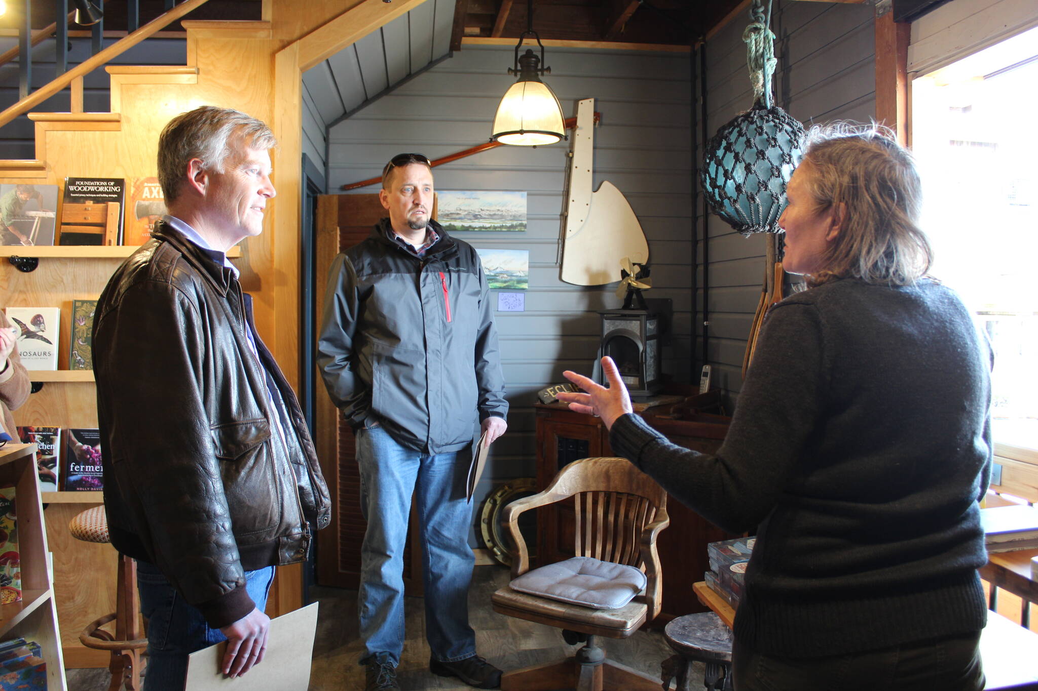 Photo by Karina Andrew/Whidbey News Group
<em>State Reps. Dave Paul, left, and Greg Gilday learn about the historic preservation work that took place in Kingfisher Bookstore from Meg Olsen, the store’s owner. The original harbor door on the building’s lower level was used when the building housed a confectionary.</em>