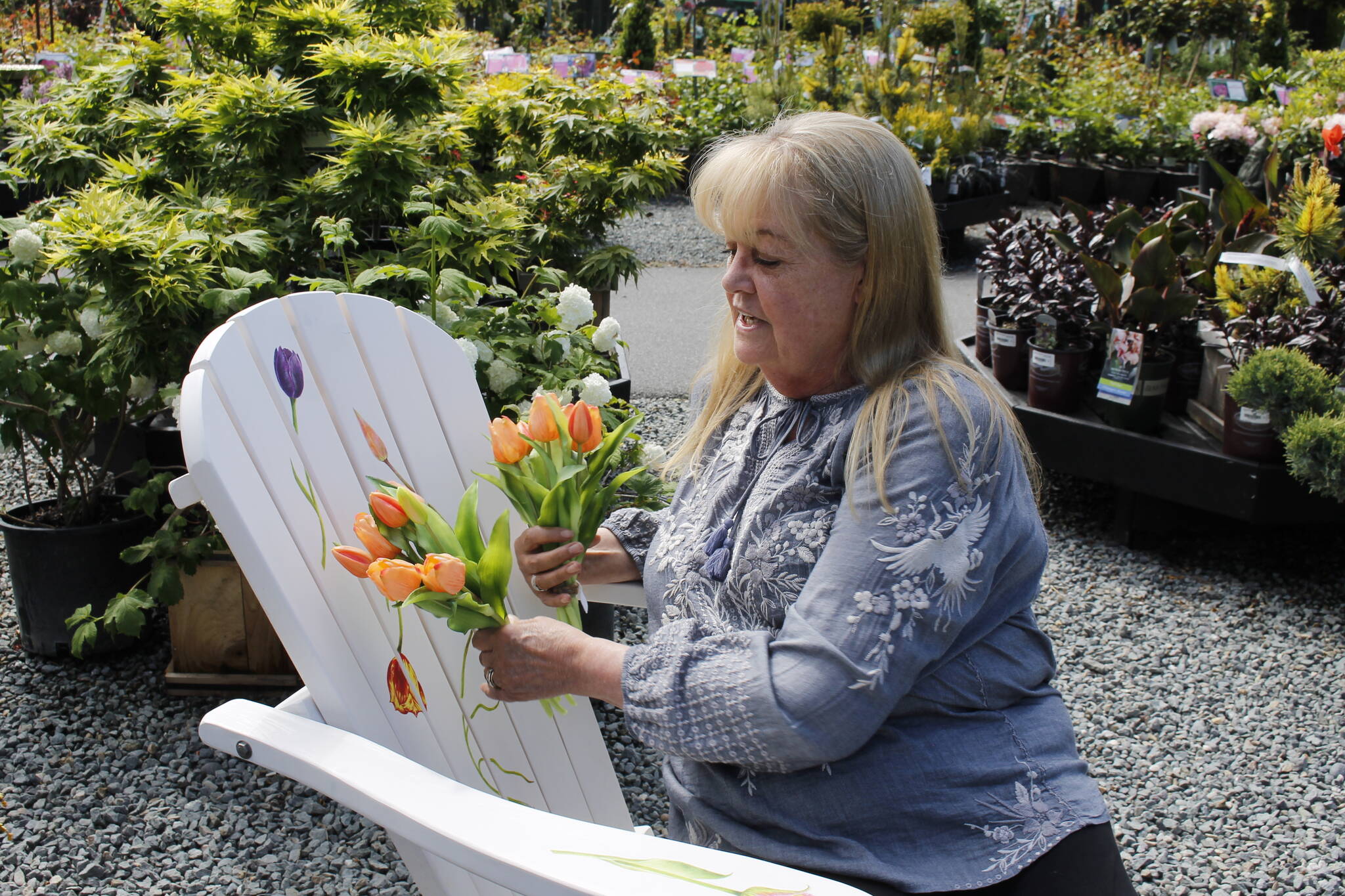 Photo by Kira Erickson/South Whidbey Record
Deborah Montgomerie traces a tulip painted on her chair, which is titled “Tulip Mania” after a period in history where prices of tulip bulbs soared in Holland.