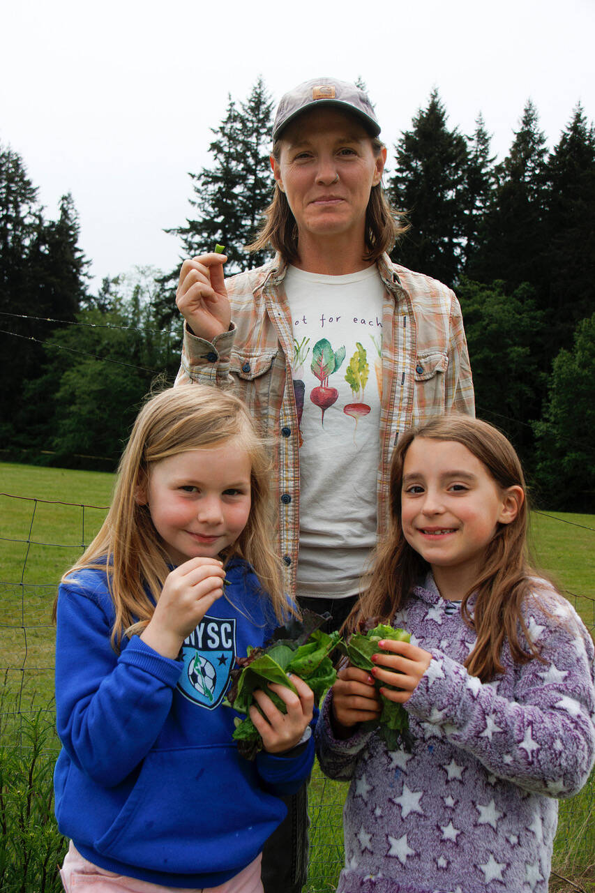 South Whidbey School Farms Manager Emily Koller enjoys some snap peas fresh from the farm along with Charlotte Bunch and Simone Boland, who made veggie tacos out of fresh lettuce. (Photo by David Welton)