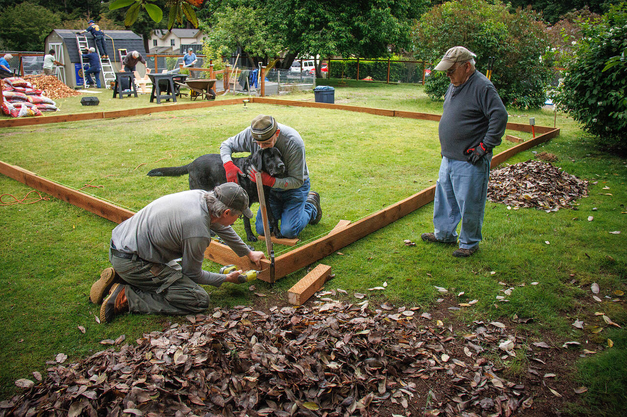 Photos by David Welton
From left to right, Jan-Marc Jouas, Russ DeWolfe and David LaBreque of Rotary Club of South Whidbey Island, with assistance from service dog Theo, work on building an enclosure for a playground in the backyard of the House of Hope.
