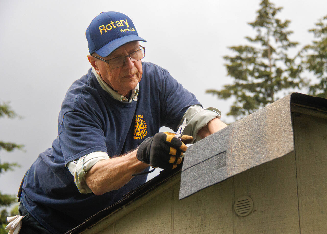 Jim Rogers of Rotary Club of Whidbey Westside reroofs a storage shed at the House of Hope.